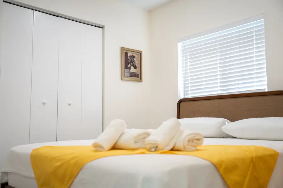 Guest bedroom with yellow throw and folded towels
